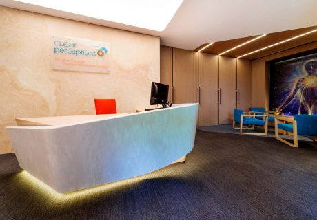 office reception with stone reception desk and wall, and waiting lounge with timber floor to ceiling walls